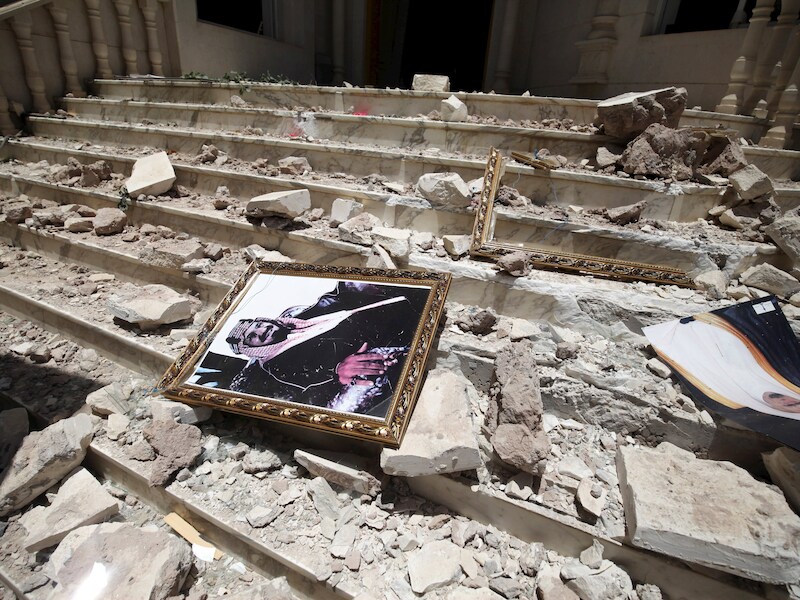 Een portret van koning Salman bin Abdulaziz tussen de brokstukken na een aanval in Sanaa (21 april).
