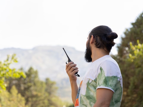 Illustratiebeeld van een man met een walkietalkie in de natuur.