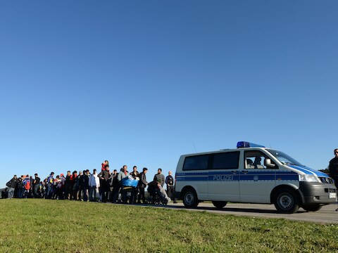 Vluchtelingen wachten achter een politiewagen aan de Duits-Oostenrijkse grens.