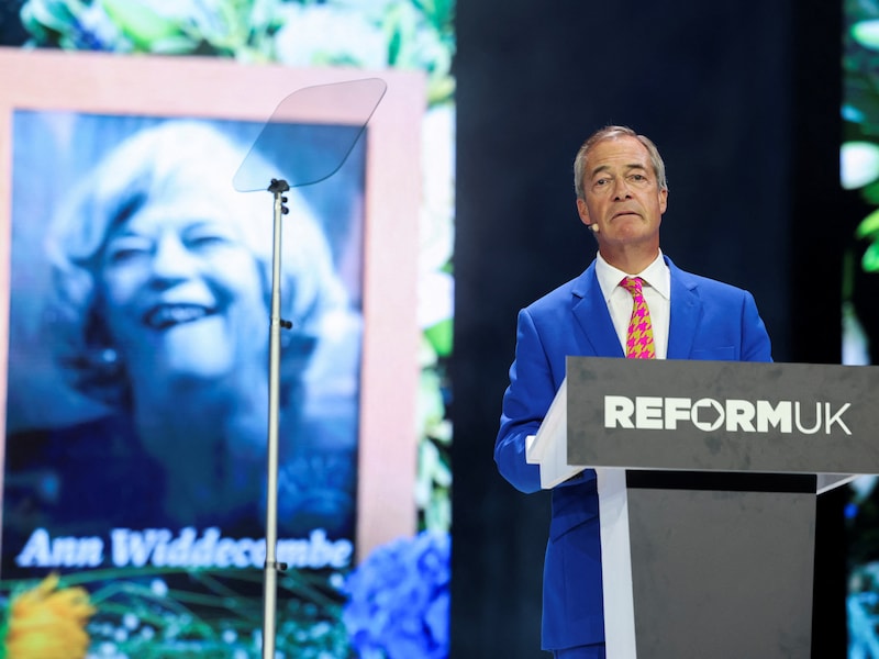 Nigel Farage op een conferentie met achter zich een eerbetoon aan de overleden Ann Widdecombe.