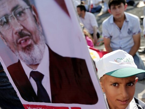 Een kind draagt een foto van Mursi.