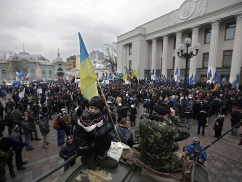 Betogers staan voor het parlementsgebouw in Kiev terwijl het parlement zich binnen vergadert over de nieuwe coalitieregering.