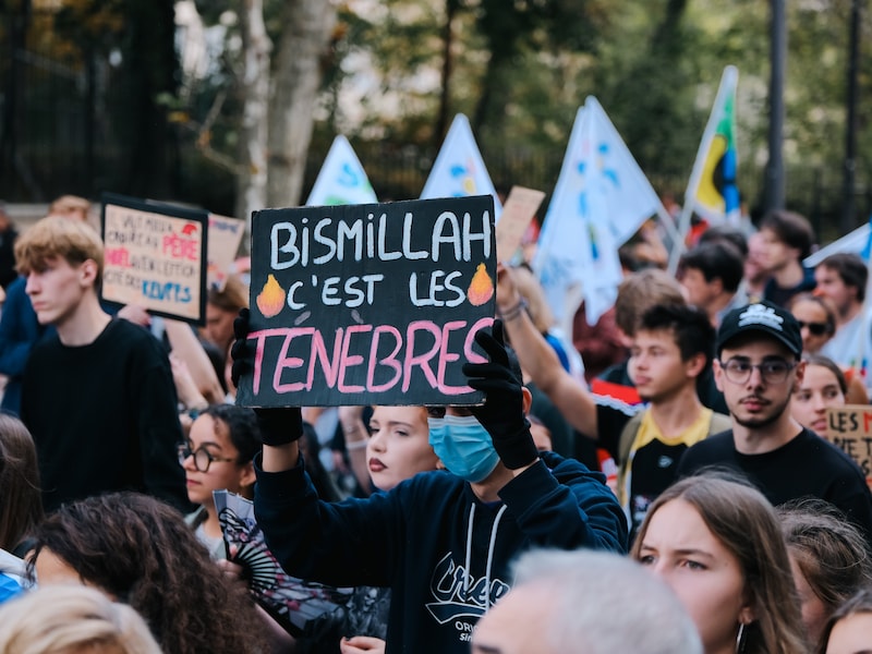 Een student houdt een bord vast met de tekst: ‘Bismillah, het is de duisternis’ tijdens de scholierenprotesten in Parijs. 