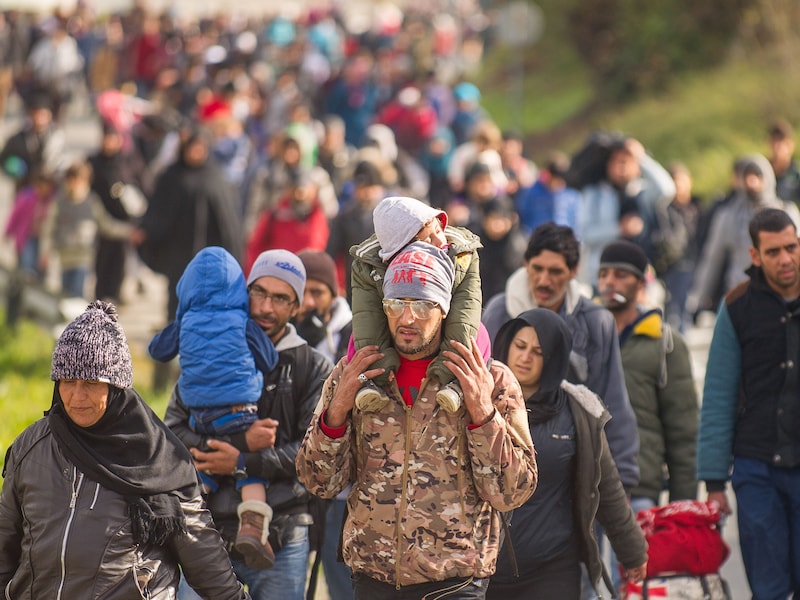 Soldaten begeleiden vluchtelingen op een weg bij Sentilj, Slovenië om de grens over te steken.