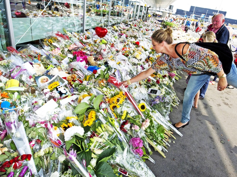 Een vrouw legt op Schiphol bloemen neer ter nagedachtenis van de slachtoffers van de neergehaalde MH17.
