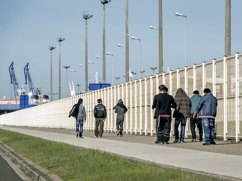 Migranten wandelen in de haven van Calais.