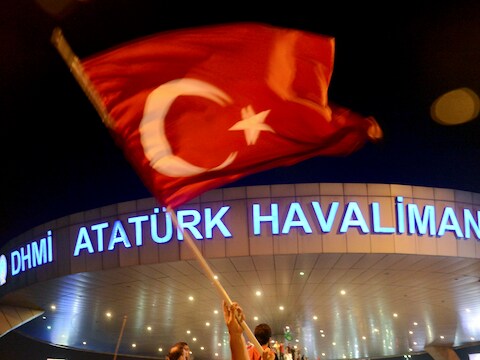 Een man zwaait met een Turkse vlag voor luchthaven Ataturk in Istanboel