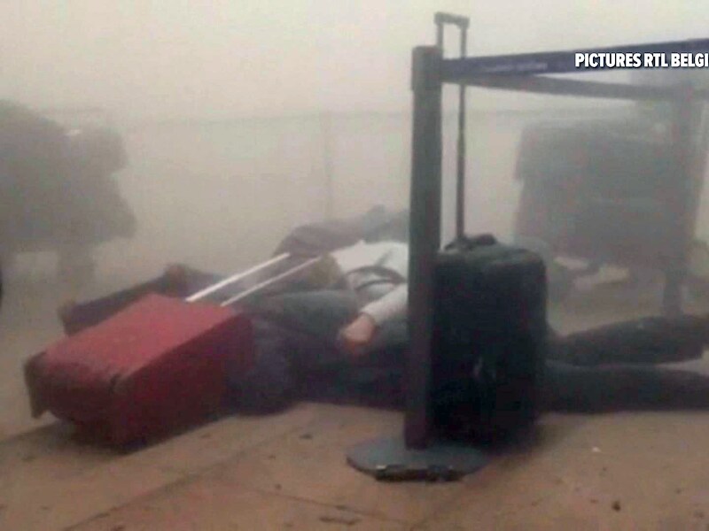 Reizigers zoeken in de luchthaven van Zaventem beschutting onder hun koffers.