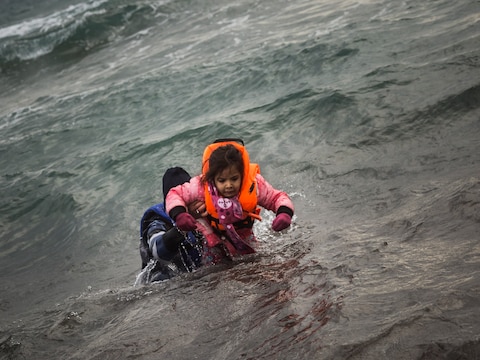 Een vrijwilliger helpt een kind naar het strand op het Griekse eiland Lesbos.