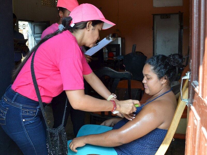 Colombiaanse vrouwen krijgen muggenwerende spray opgespoten.