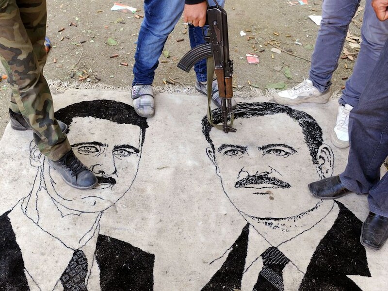 Een afbeelding van president Assad en zijn vader Hafez, de vorige president van Syrië, worden vertrapt.