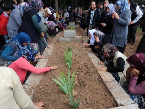 Nabestaanden rouwen bij de graven van slachtoffers.