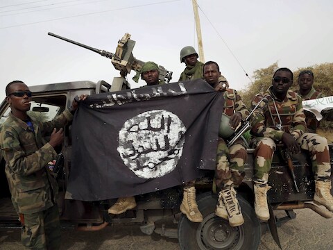 Nigeriaanse soldaten houden een in beslag genomen vlag van Boko Haram vast.
