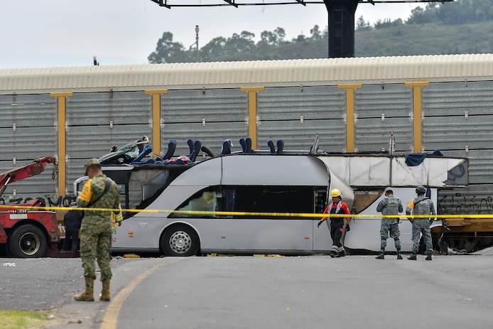 Militairen en brandweermannen bij de beschadigde bus.