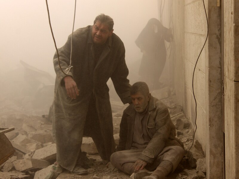 Een Syrische man helpt een gewonde man onder het puin vandaag in Aleppo, waar vandaag opnieuw luchtaanvallen zijn gepleegd.
