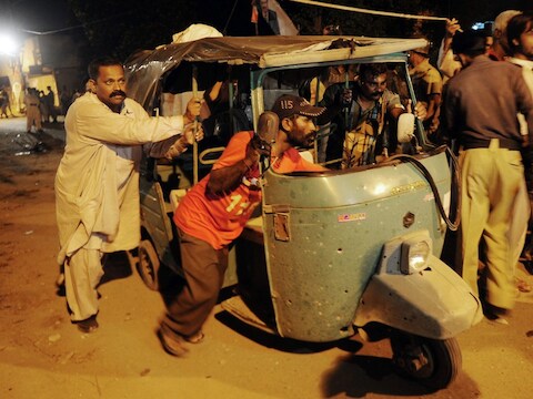 Pakistaanse mannen slepen het wrak weg waarin de bom verstopt lag.