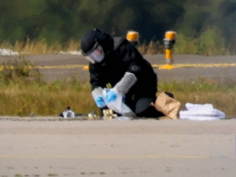 Een agent in beschermende kledij aan het werk op de luchthaven van Leipzig.