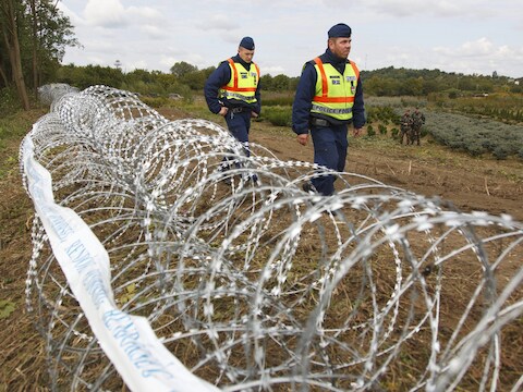 Hongaarse politieagenten patrouilleren langs het voorlopige 'hek' op de grens tussen Hongarije en Kroatië.
