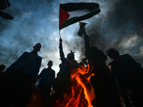 Indonesische betogers houden de Palestijnse vlag in de lucht terwijl ze een Israëlische en Amerikaanse vlag verbranden.