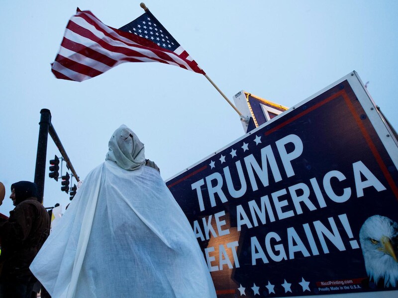 Een demonstrant met een imitatiegewaad van de KKK bij een Trump-bijeenkomst