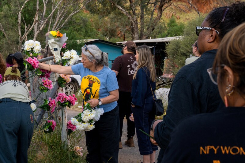 People place flowers on a fence around the Ilyperenye town camp outside Alice Springs, where Kumanjayi Little Baby was abducted. Town camps are residential communities located outside regional towns in Australia and inhabited by Aboriginal families.