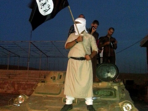 Aanhangers van Islamitische Staat bij een buitgemaakte tank na de inname van Mosoel op 23 juni 2014.