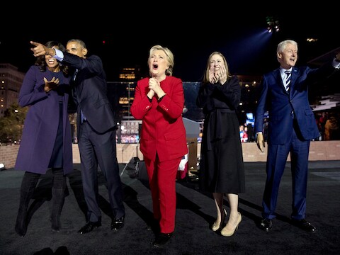 Hillary Clinton in het rood, samen met oud-president Obama en zijn vrouw Michelle en haar dochter Chelsea en man Bill Clinton.