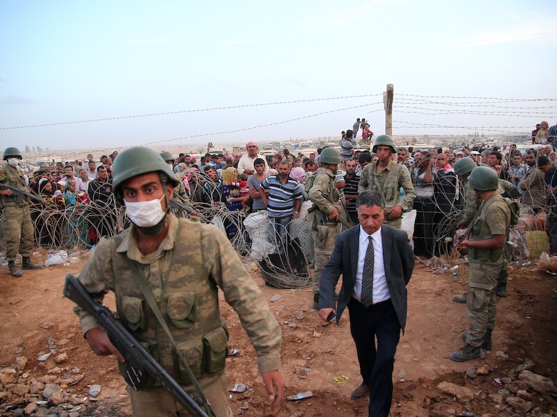 Turkse soldaten bewaken Syrische vluchtelingen die net de grens zijn overgestoken op de vlucht voor het geweld van IS.