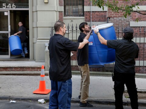 In hermetisch afgesloten tonnen wordt de inhoud van het appartement van de besmette arts in New York afgevoerd.