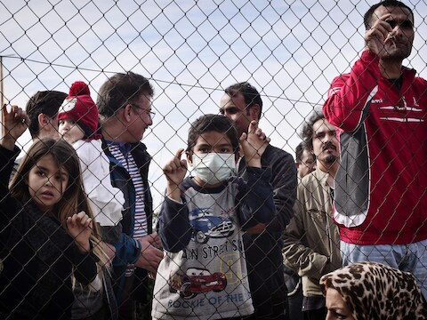 Vluchtelingen achter een hek in een kamp in Athene. Griekenland en Italië krijgen daar aangekomen vluchtelingen en migranten amper naar andere lidstaten versluisd.