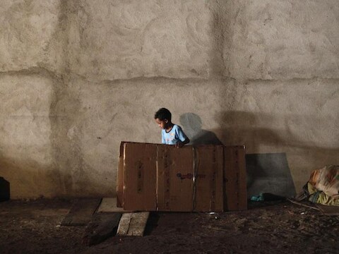 Een kind maakt een bed van karton tijdens de bezetting van een leegstaand gebouw door krakers in het Braziliaanse Sao Paulo.