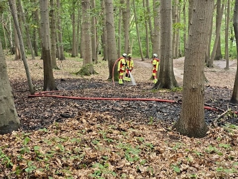 De brandweer zorgt ervoor dat de ondergrond goed nat is en het vuur niet kan heropflakkeren.