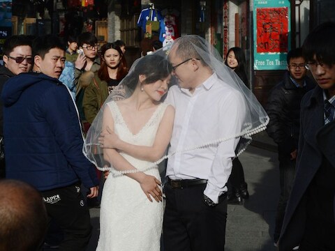 Een jong stel poseert op straat in Peking voor een trouwfoto