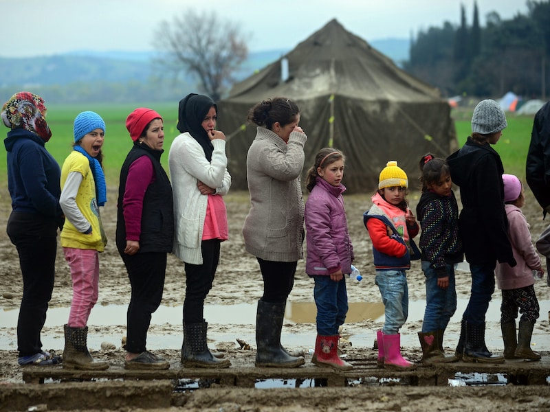 Vluchtelingen staan in de rij voor thee in het kamp op de Grieks-Macedonische grens in Idomeni.