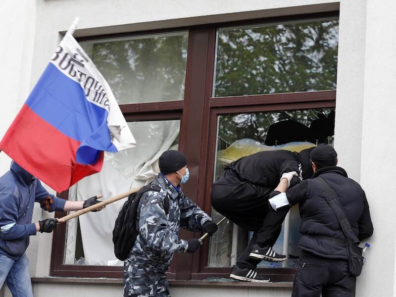 Pro-Russische activisten in Loehansk slaan de ruiten van het lokale overheidsgebouw in Loehansk kapot.