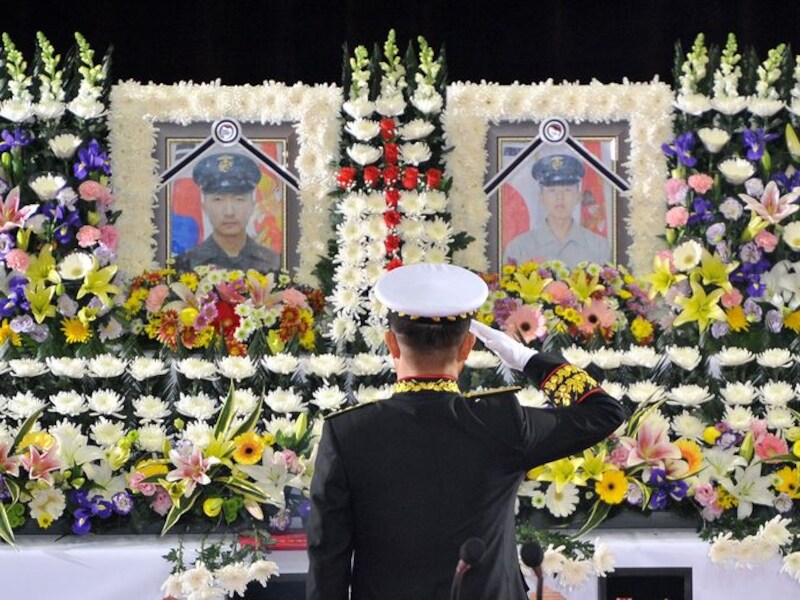 Yoo Nak-Joon, stafchef van Zuid-Koreaanse marine, groet de foto's van twee omgekomen soldaten bij de beschieting door Noord-Korea