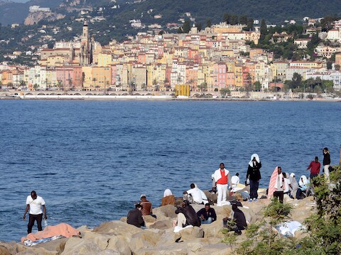 Tientallen vluchtelingen hebben afgelopen weekend de nacht doorgebracht op de rotsen van Ventimiglia, Italië. In de achtergrond is de Franse stad Menton te zien.