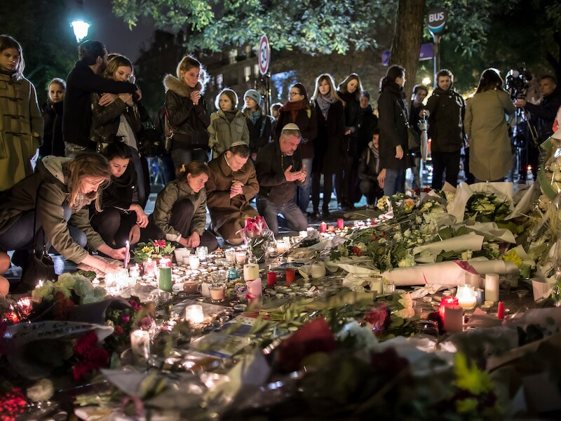Mensen leggen bloemen en plaatsen kaarsen aan de Bataclan in Parijs als eerbetoon aan de slachtoffers van de aanvallen op vrijdag 13 november.