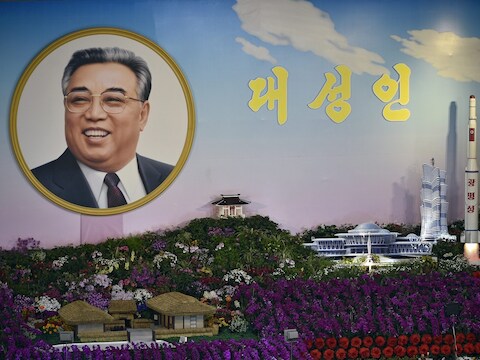 Foto van een bloemenexpositie in Pyongyang waar de Koreaanse grondlegger en een raket naast elkaar staan.
