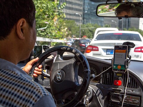 Een taxichauffeur die in Peking de app van Didi gebruikt.