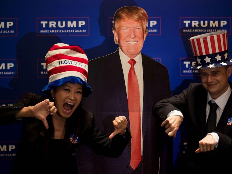 Een koppel poseert voor een kartonnen Donald Trump tijdens een verkiezingsevenement dat het Amerikaanse consulaat in Shangai organiseerde.