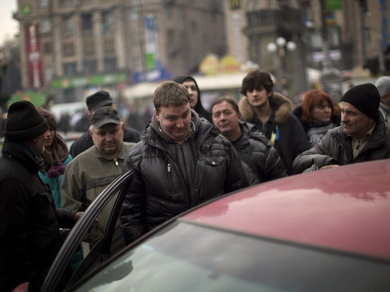 Janoekovitsj-opposanten luisteren naar zijn persconferentie op een autoradio in Kiev.