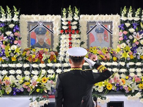 Yoo Nak-Joon, stafchef van Zuid-Koreaanse marine, groet de foto's van twee omgekomen soldaten bij de beschieting door Noord-Korea