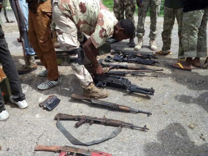 Een soldaat van het Nigeriaanse leger neemt wapens van Boko Haram-strijders in beslag.