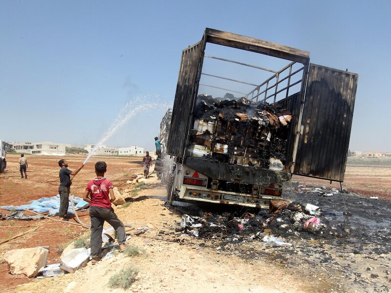 Mannen blussen een brandje in een vrachtwagen nadat die in brand vloog na een luchtaanval in de door rebellen gecontroleerde stad Atareb in de provincie Aleppo.