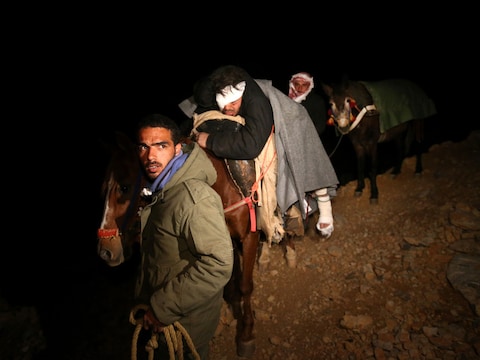 Een gewonde Syrische man wordt per paard in veiligheid gebracht. Hij werd geraakt door een tankgranaat toen hij brood naar het dorp Beit Jinn wilde brengen.