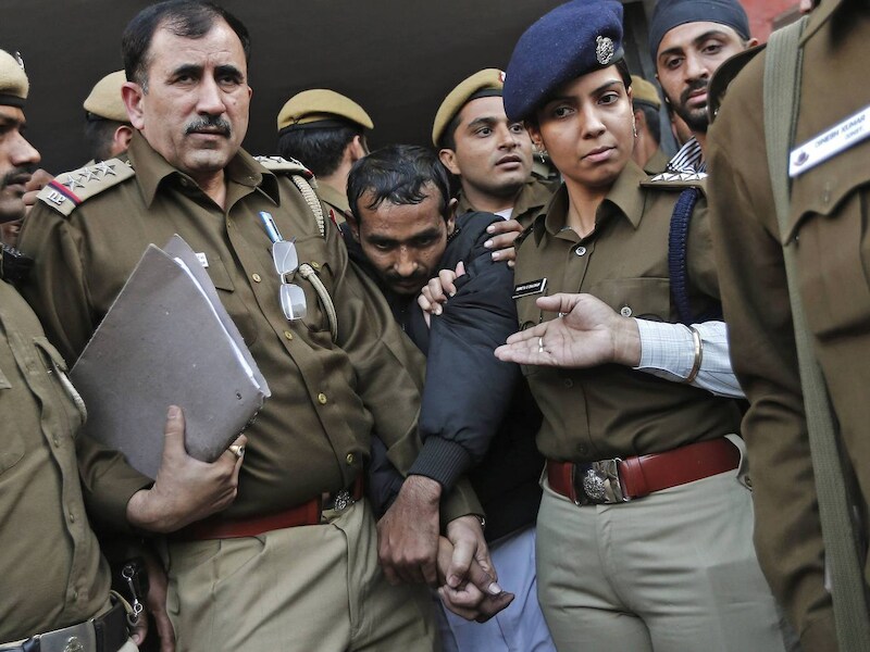 De chauffeur die van verkrachting beschuldigd wordt te midden van politieagenten in de Indiase hoofdstad New Delhi.