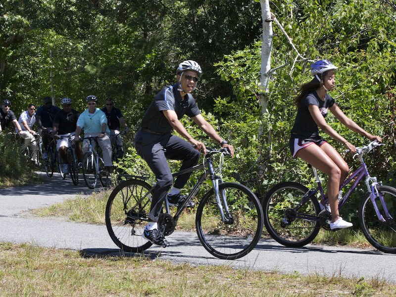 Barack Obama maakt tijdens zijn vakantie een fietstochtje met zijn dochter Malia, waarbij hij gevold wordt door beveiligers