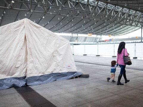Een vluchtelinge wandelt met haar kind aan de hand voorbij een tent aan de expohal in Stuttgart.