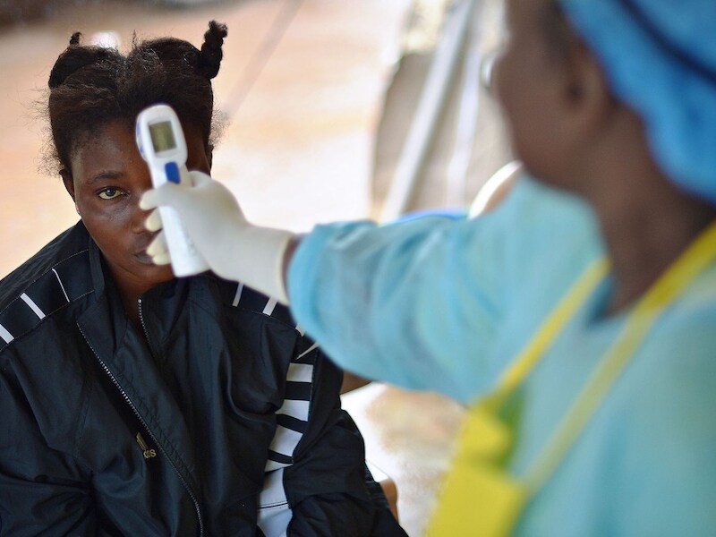 Een hulpverlener in Sierra Leone neemt de temperatuur op van een patiënt bij wie ebola wordt vermoed